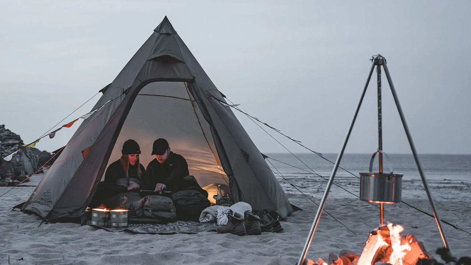Lifestyle image of the Easy Camp Otra Tipi tent on a sandy beach, perfect for festival camping by the sea.