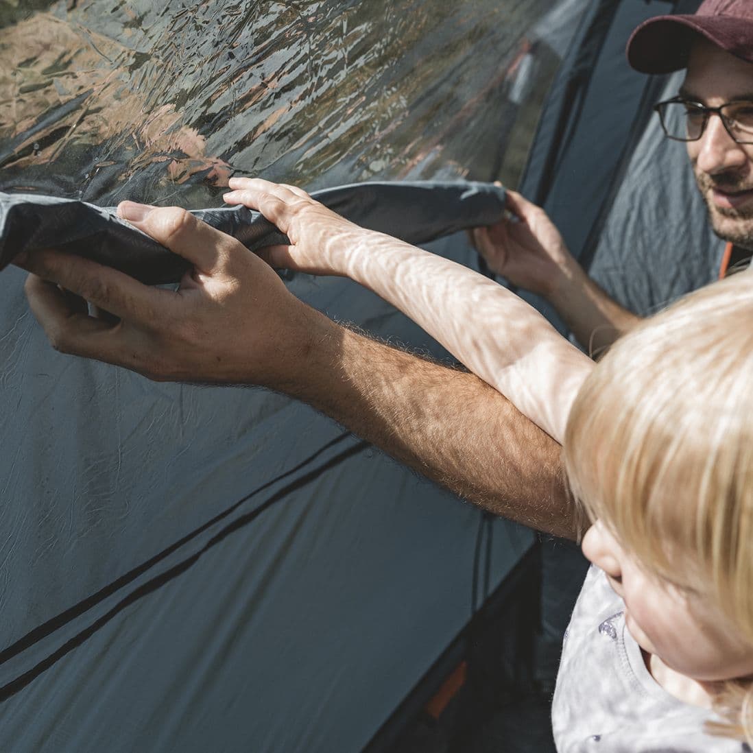 Parent and child adjusting the curtain of the Easy Camp Skarvan 5 tent, a versatile 5 person tent for family camping holidays.
