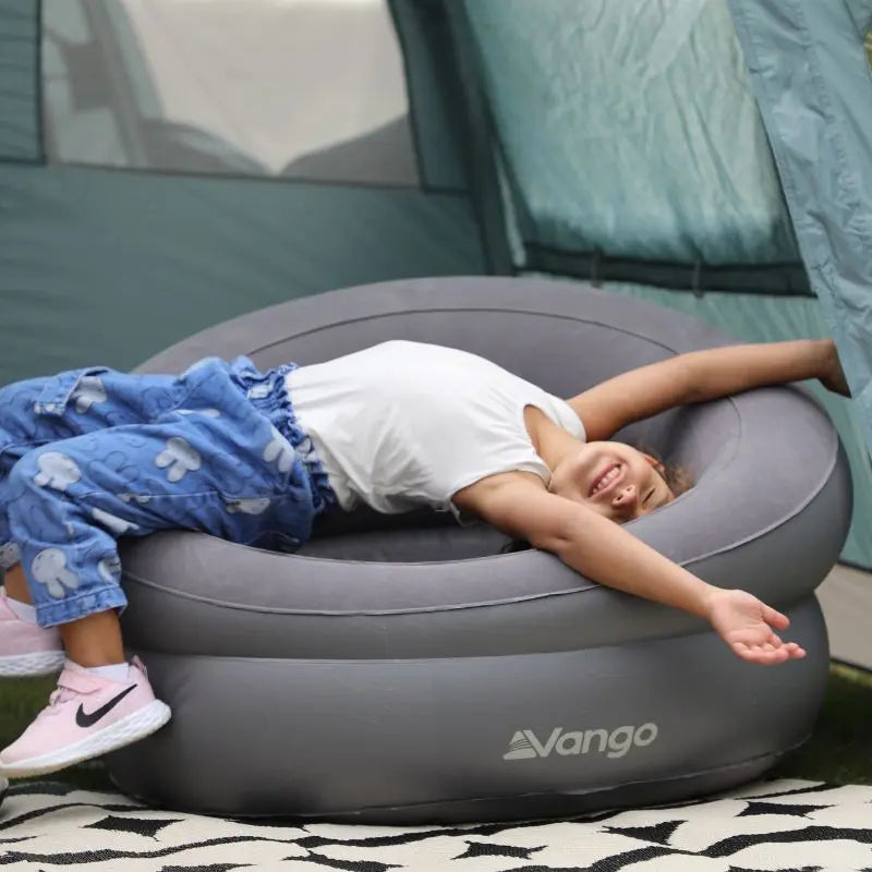 Child lying on an inflatable Vango seat in front of a tent