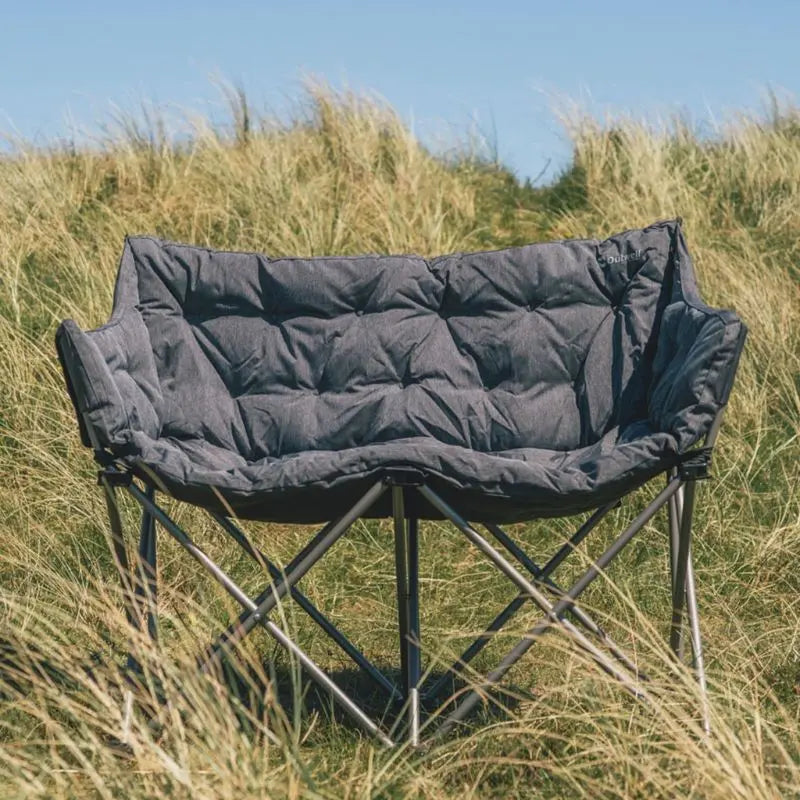 Foldable Outwell camping chair with quilted seat in a grassy outdoor setting