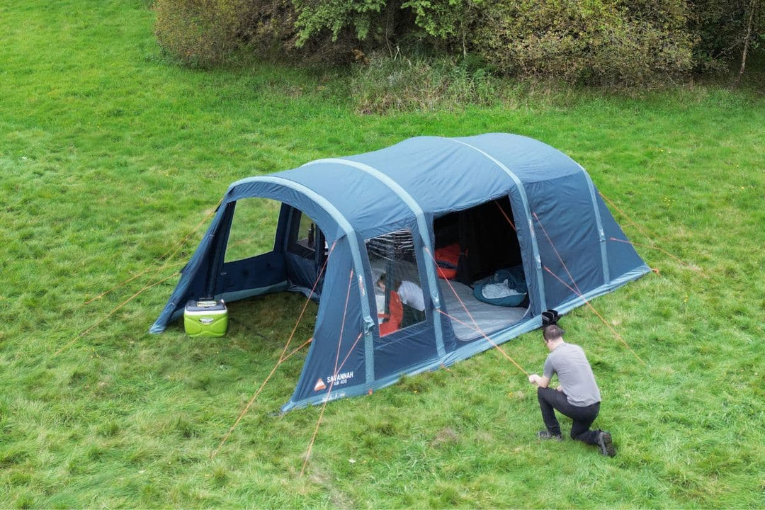 An air tent set up in a grassy field, secured with guy ropes, demonstrating AirBeam tent stability in wind. Learn about air tent wind performance and whether inflatable tents are good in strong winds.