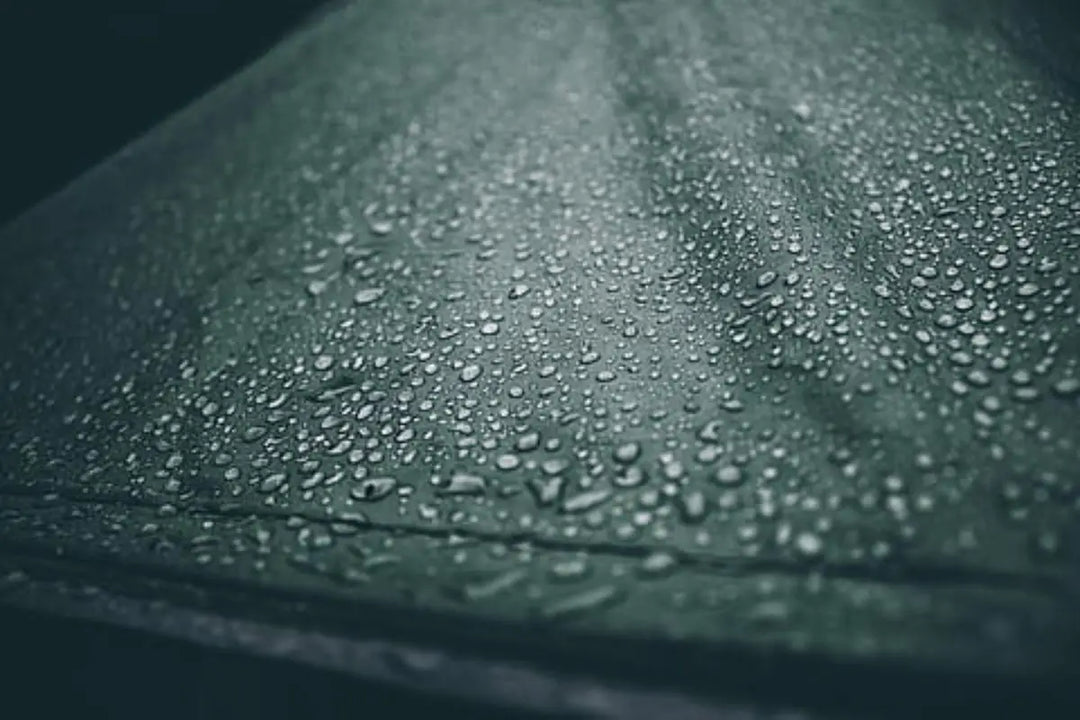 A close-up of water droplets on the fabric of a tent or awning, illustrating condensation in outdoor camping setups. Ideal for a blog discussing condensation in tents and awnings, including tips for prevention and managing moisture.