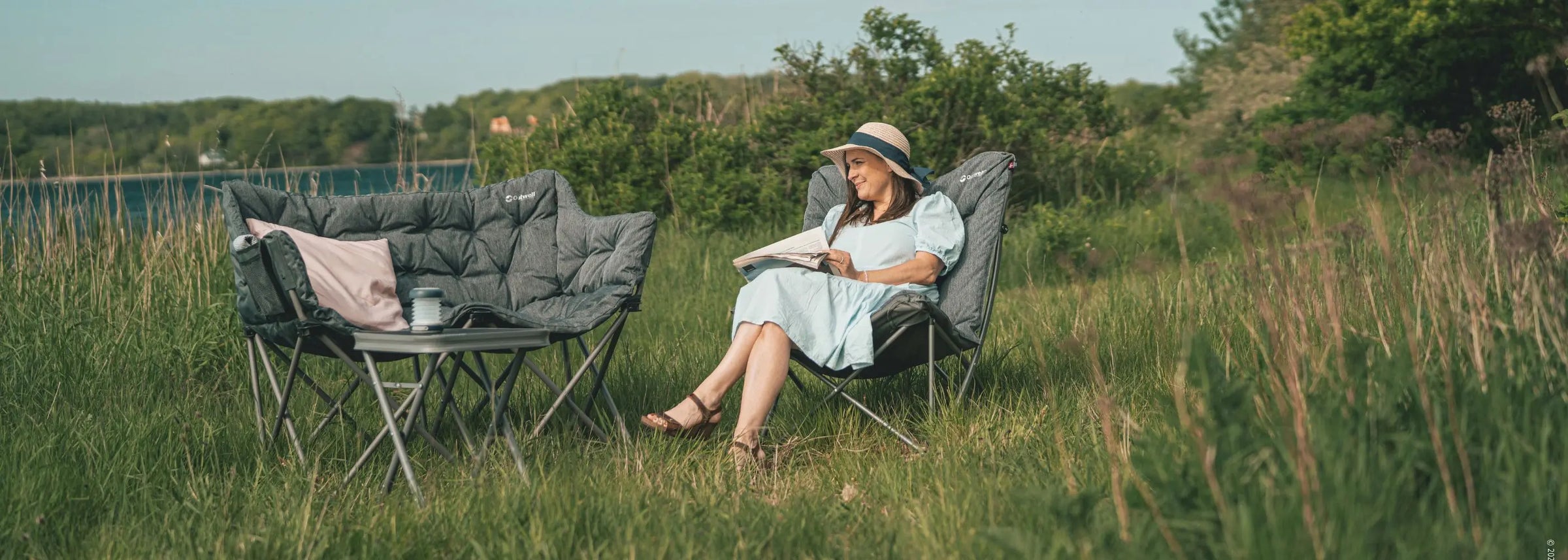 Camping Furniture Collection Page – Outwell camping furniture set up in a scenic field, featuring a cushioned sofa, and table.