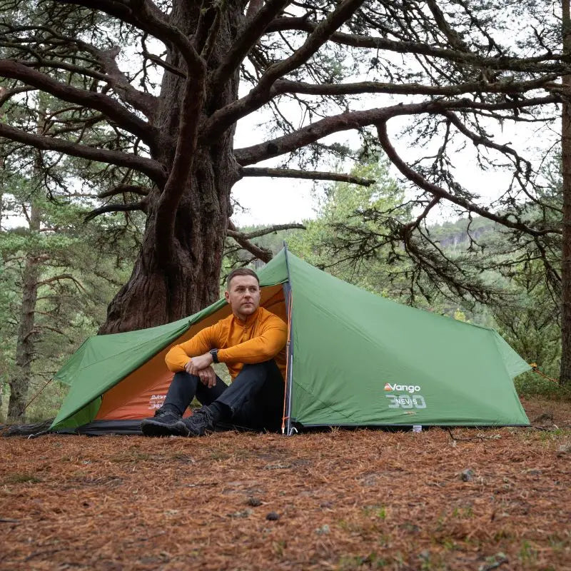 Person sitting inside a 2 man tent in a forest setting