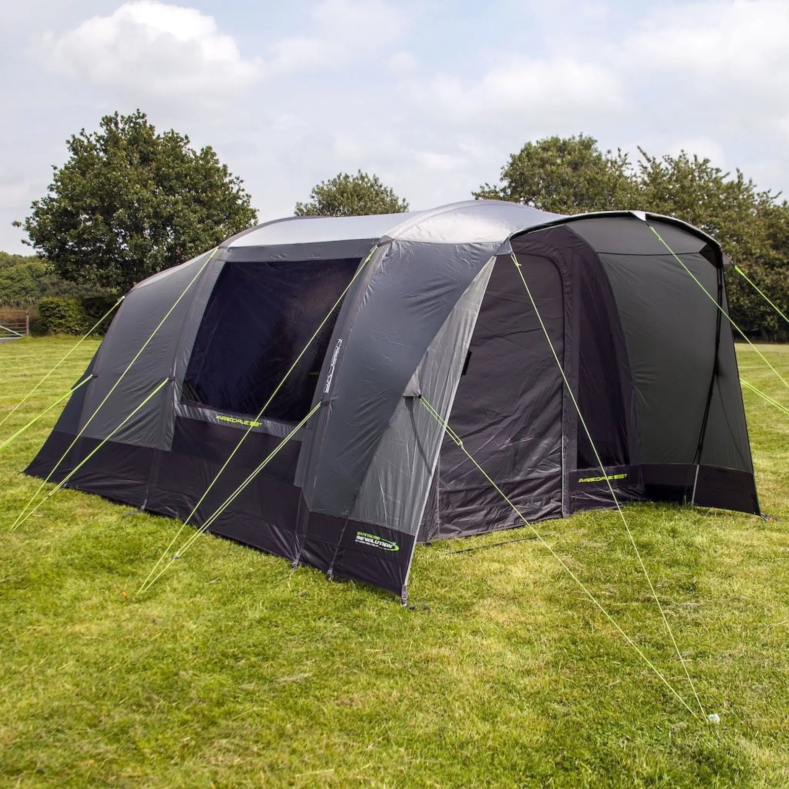 Side view of the Outdoor Revolution Airedale 400T Air Tent on grass with trees in the background