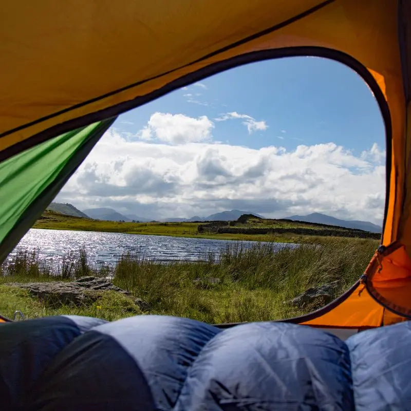 Camping scene with a backpacking tent overlooking a lake and mountains