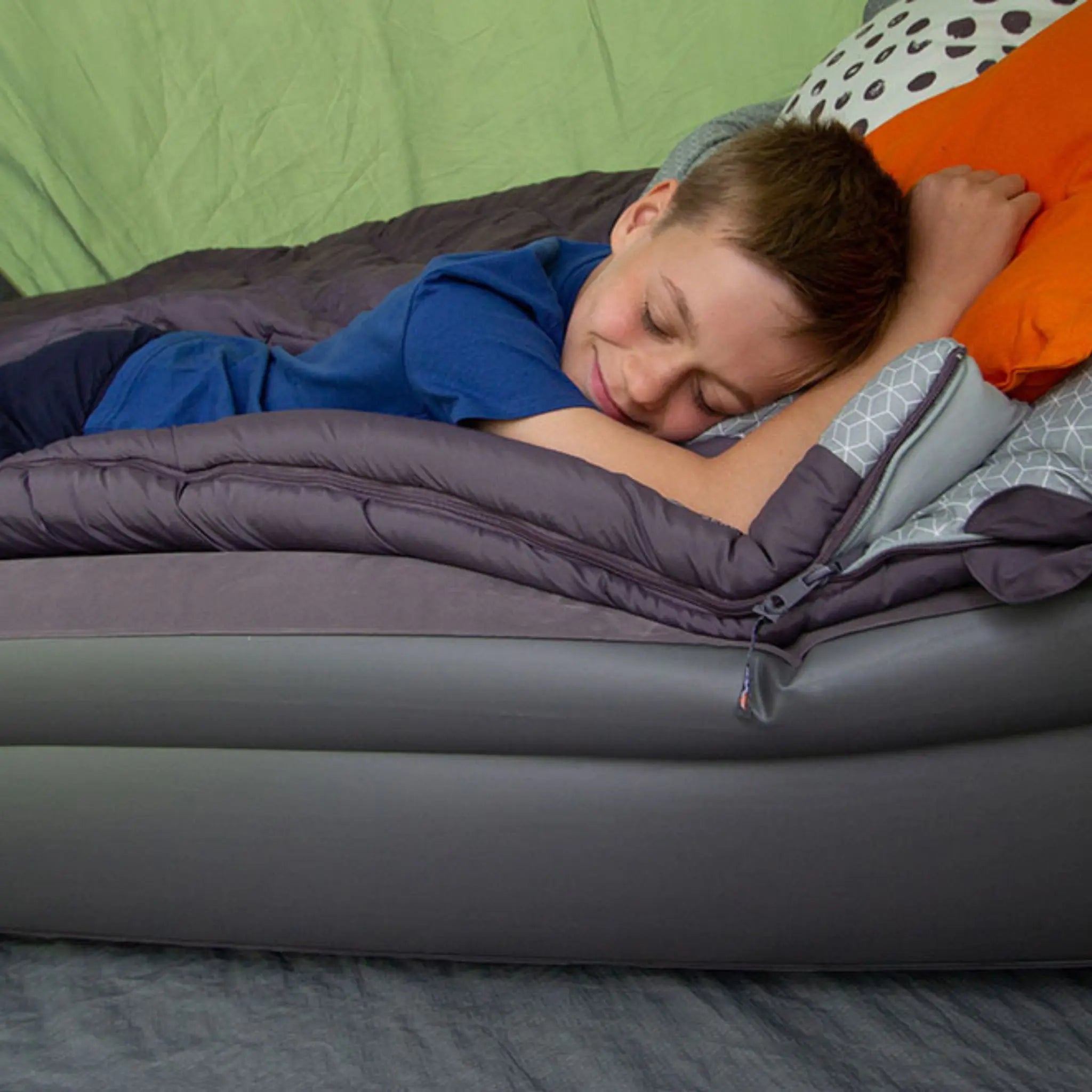 Child relaxing on a comfortable camp bed inside a tent, showcasing essential camping sleeping gear.