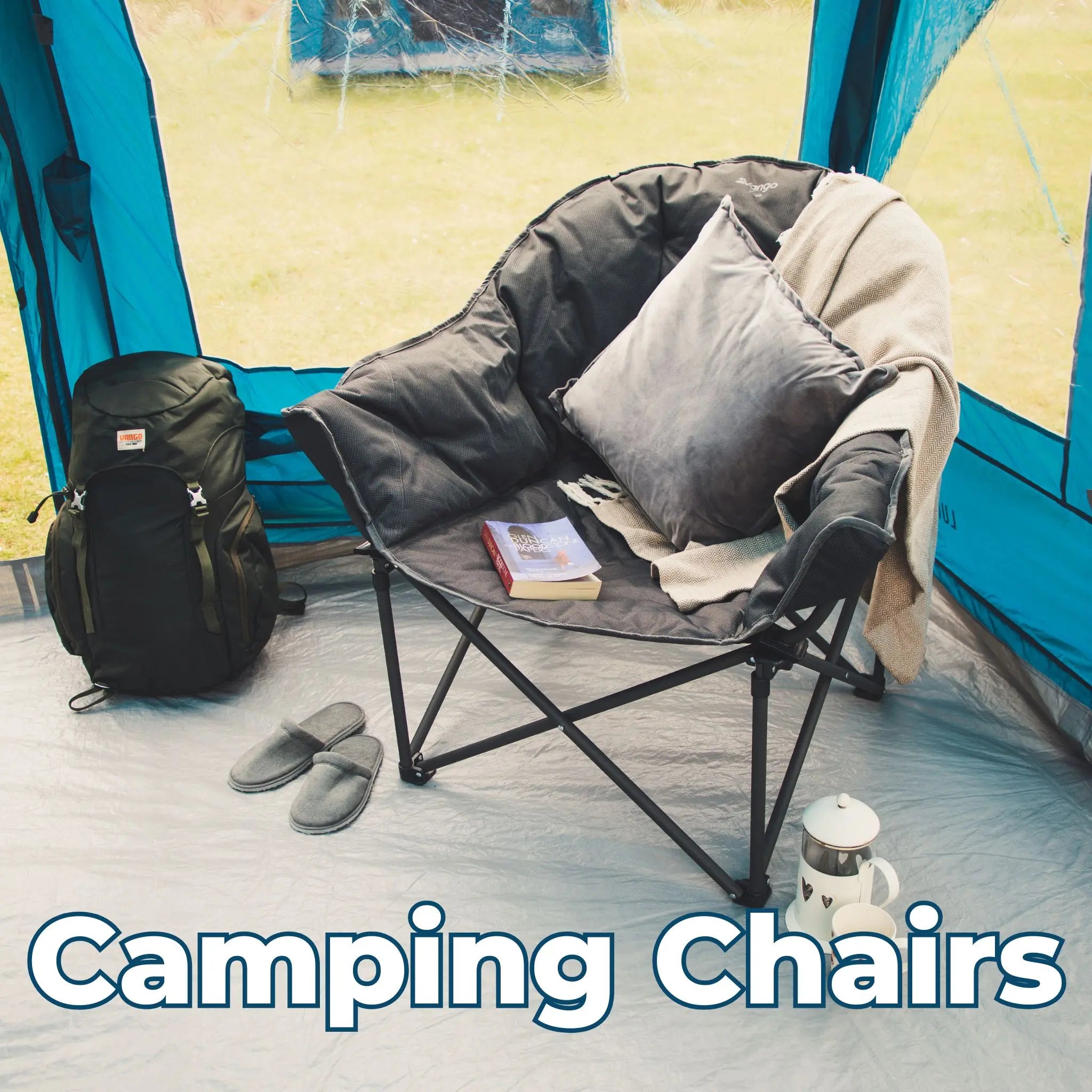 Vango Titan II Oversized camping chair set up inside a tent, complete with cushions, a book, and a cup of coffee for a comfortable retreat.