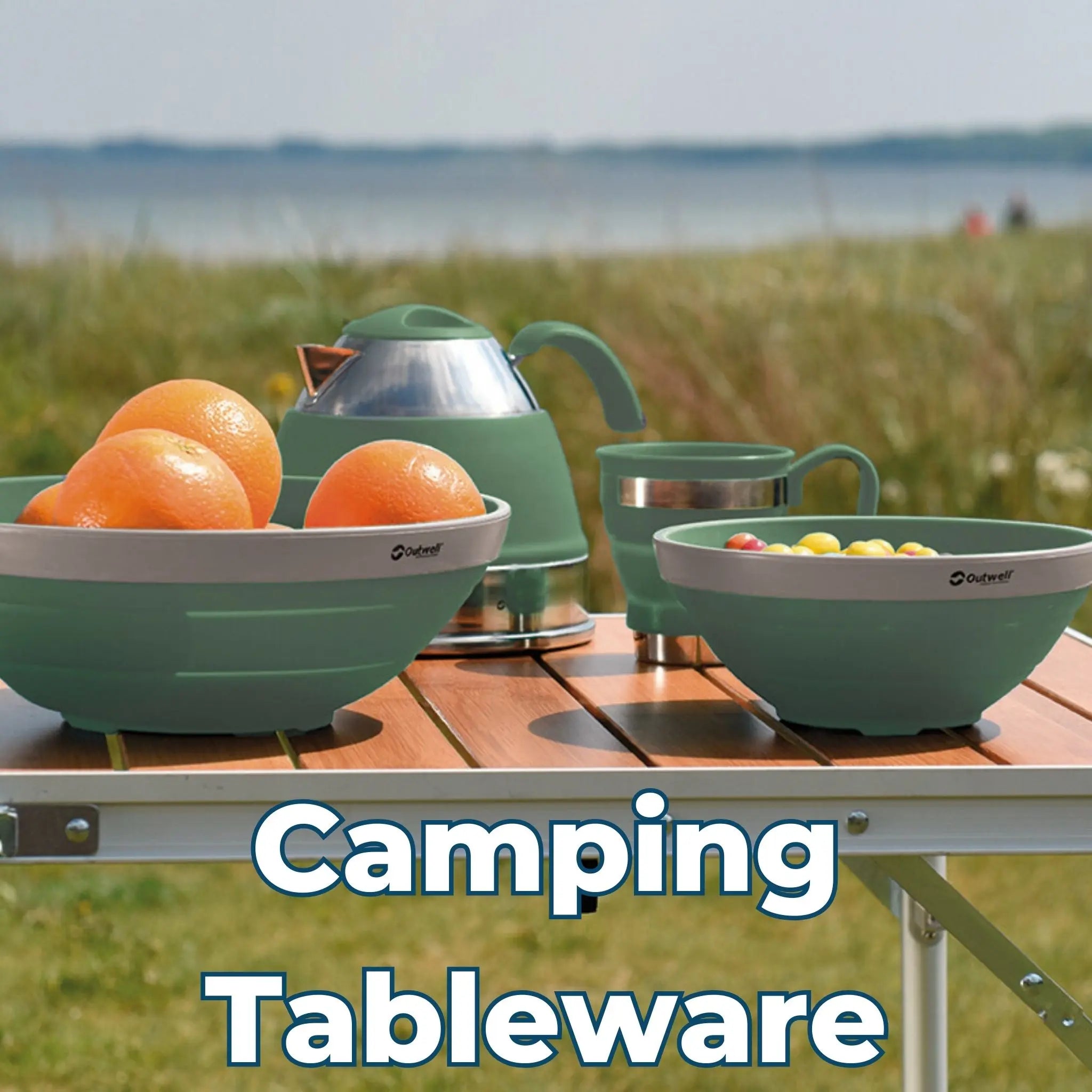 Outwell camping tableware set with collapsible bowls, a kettle, and cups on a wooden camping table by the coast.