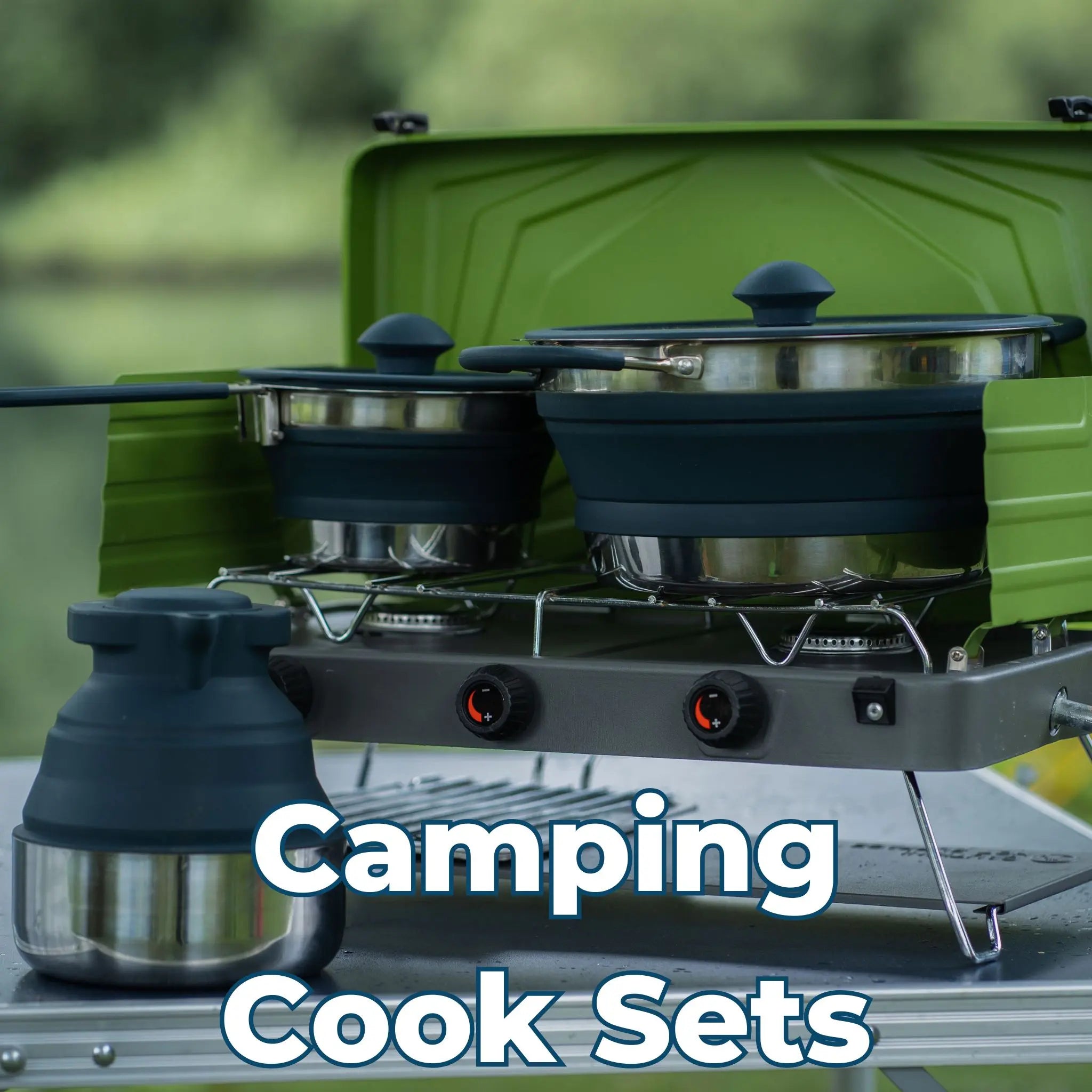 Collapsible camping cook set with pots and a kettle on a portable gas stove, set up outdoors.