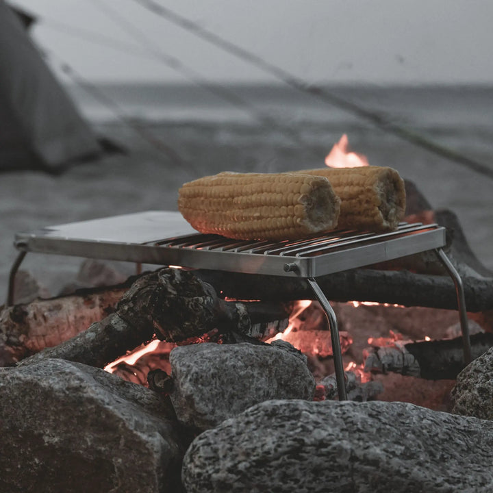 Easy Camp Campfire Grill Trivet being used on a open fire on a beach