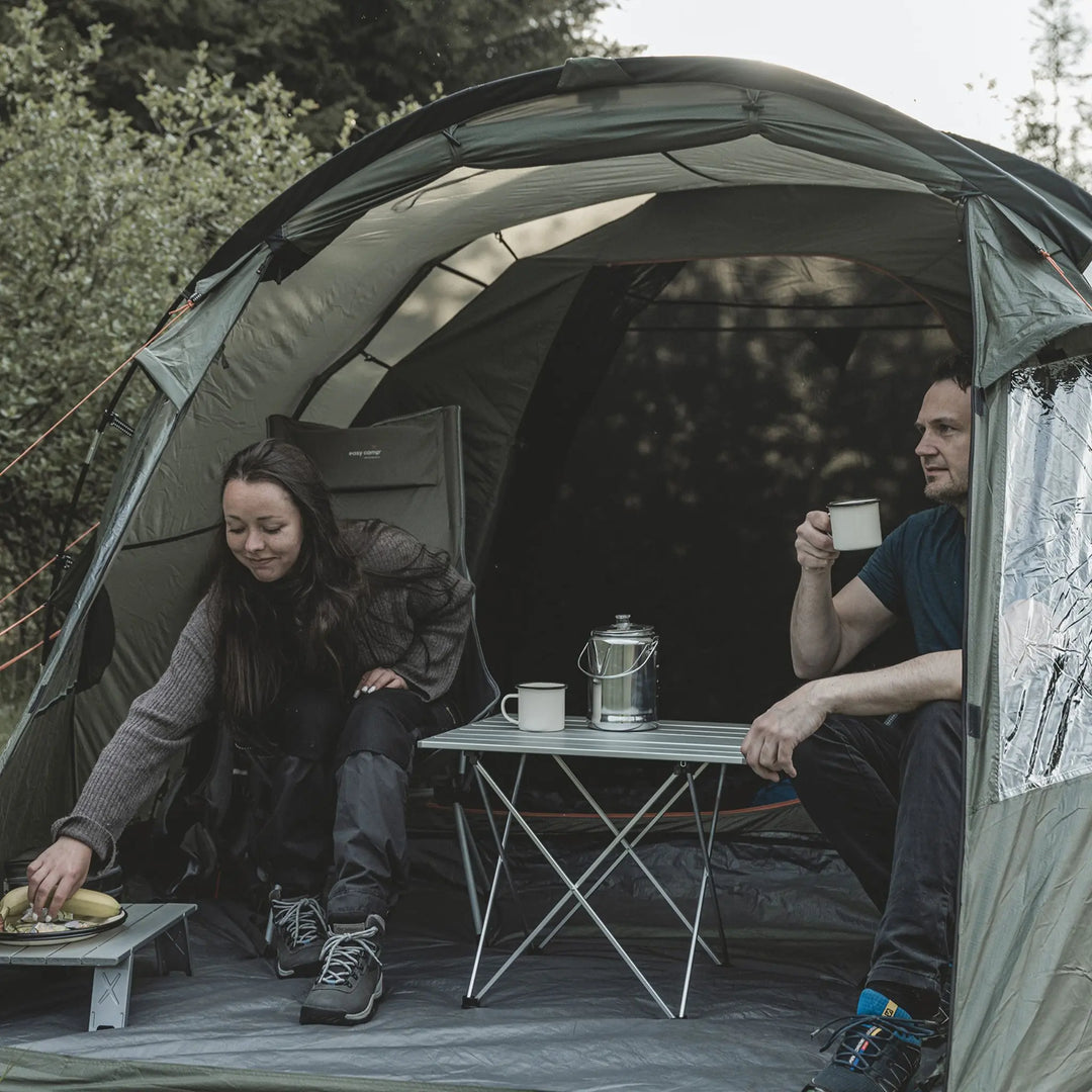 Two people inside an Easy Camp Kinn 4 Tent with a small table and coffee mugs.