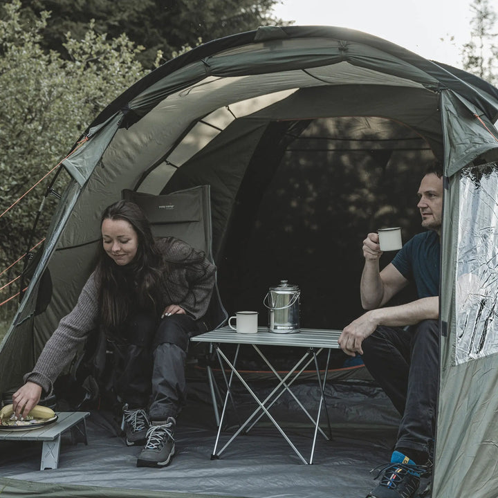 Two people inside an Easy Camp Kinn 4 Tent with a small table and coffee mugs.
