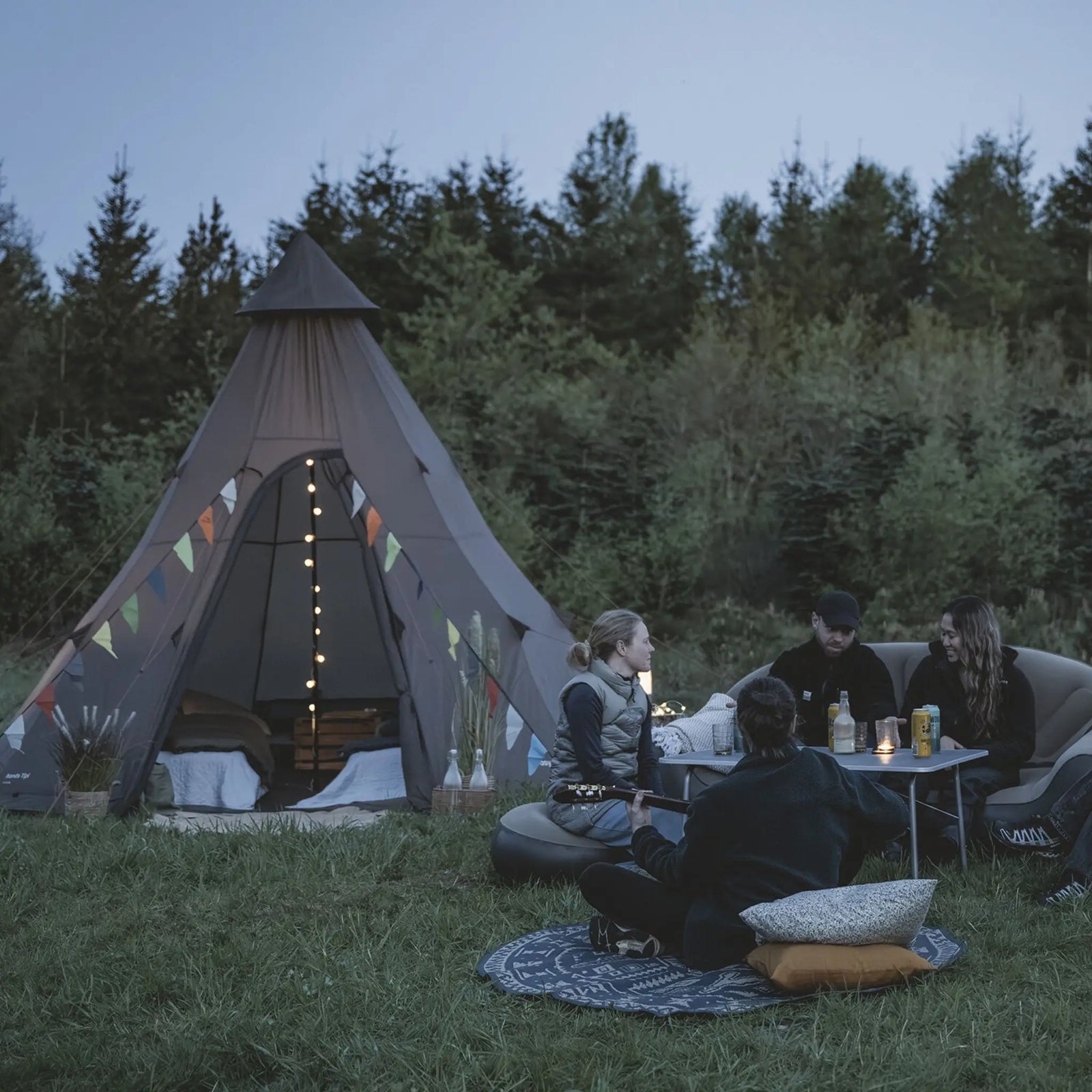 Easy Camp Rands Tipi Tent set up in a scenic outdoor setting with a group of people enjoying a relaxed evening, highlighting the spacious 8-man capacity and suitability for festivals and glamping.