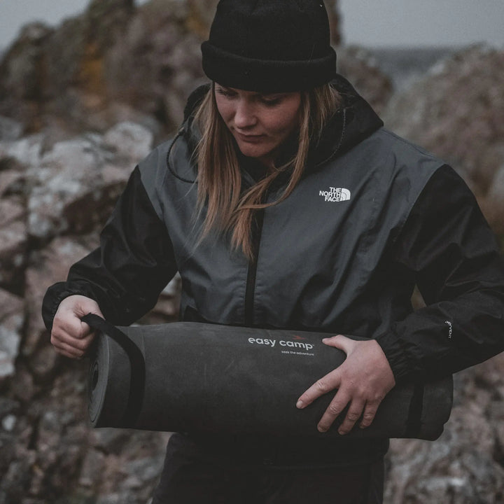 Person holding a Easy Camp Robin Basic EVA Matt with 'easy camp' branding against a rocky background