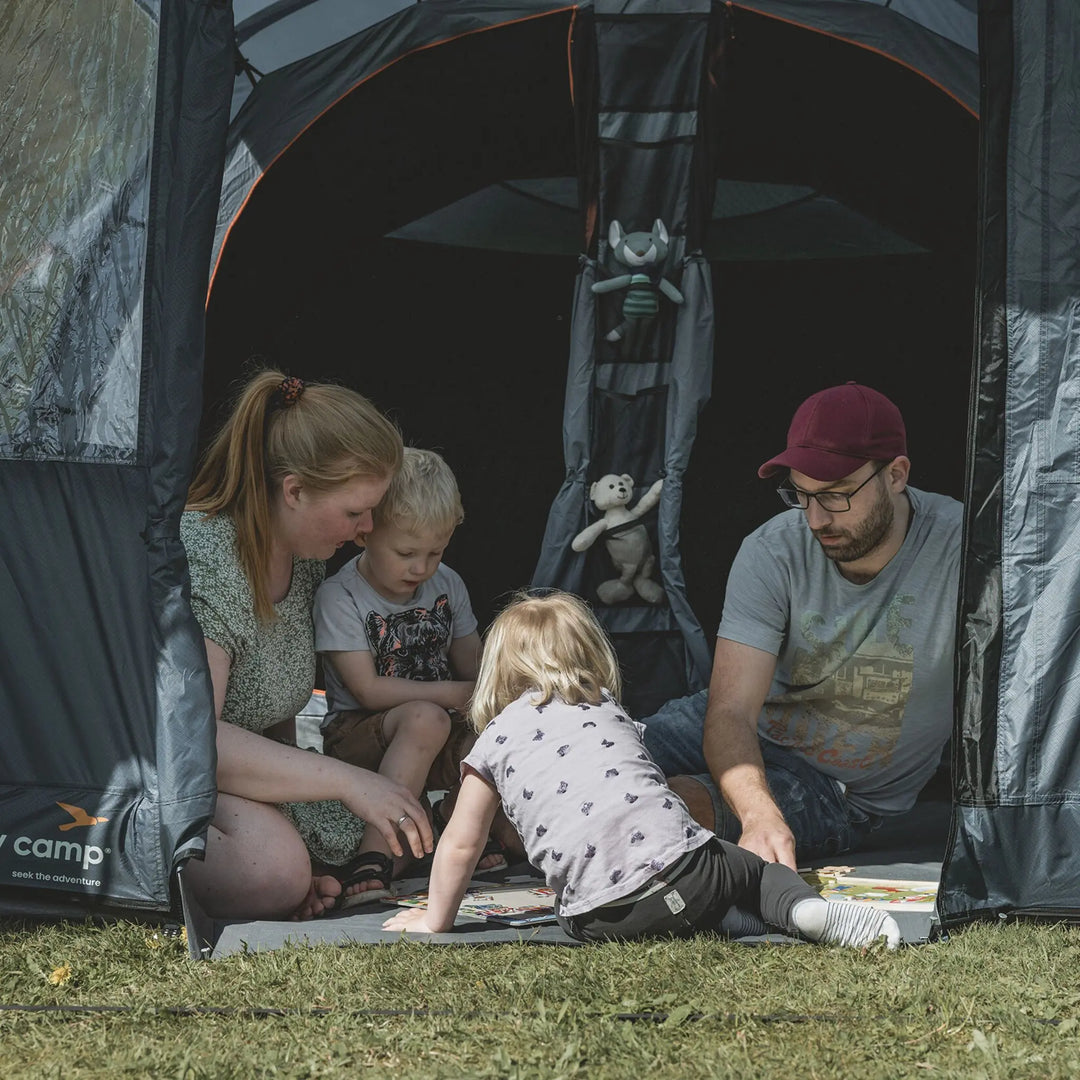 A family playing together inside the Easy Camp Skarvan 6-man tent, highlighting its spacious interior and sewn-in groundsheet.