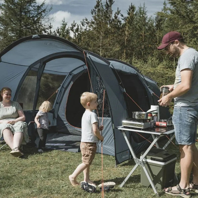 Family camping outdoors with a Easy Camp Skarvan 4 tent and cooking setup.