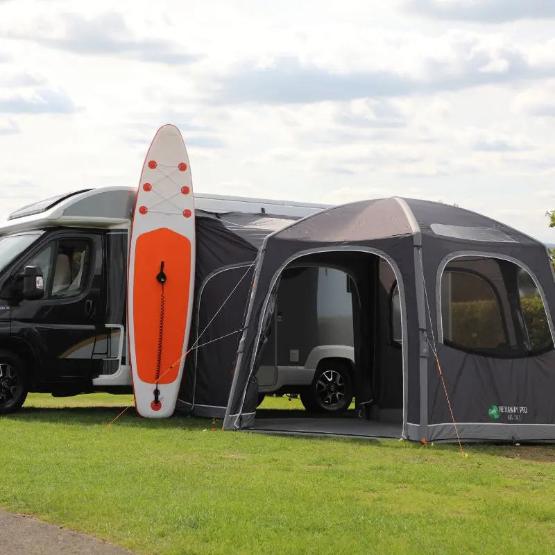 Vango Hexaway Pro Low drive away motorhome awning with an open door and orange paddleboard on a grassy area.