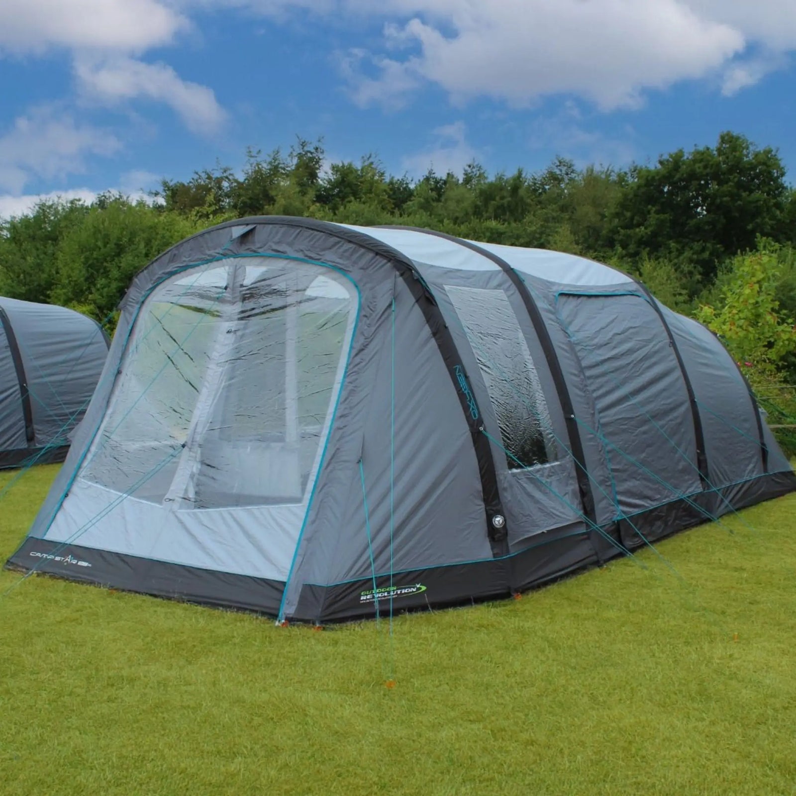 Outdoor Revolution Camp Star 500xl inflatable tent on grass with trees in the background.