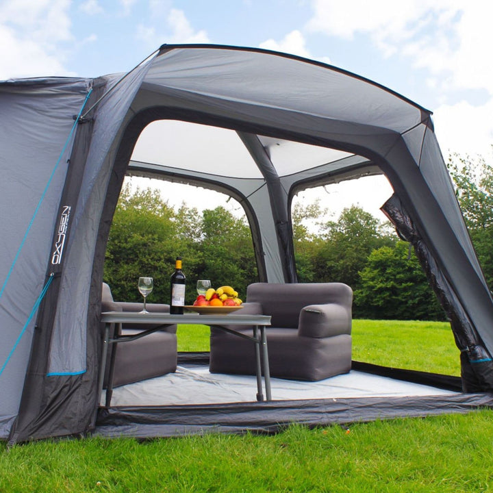 Inside the Outdoor Revolution Cayman Air Low awning, a practical camping setup includes chairs and a table, demonstrating its suitability for outdoor living with ample space.