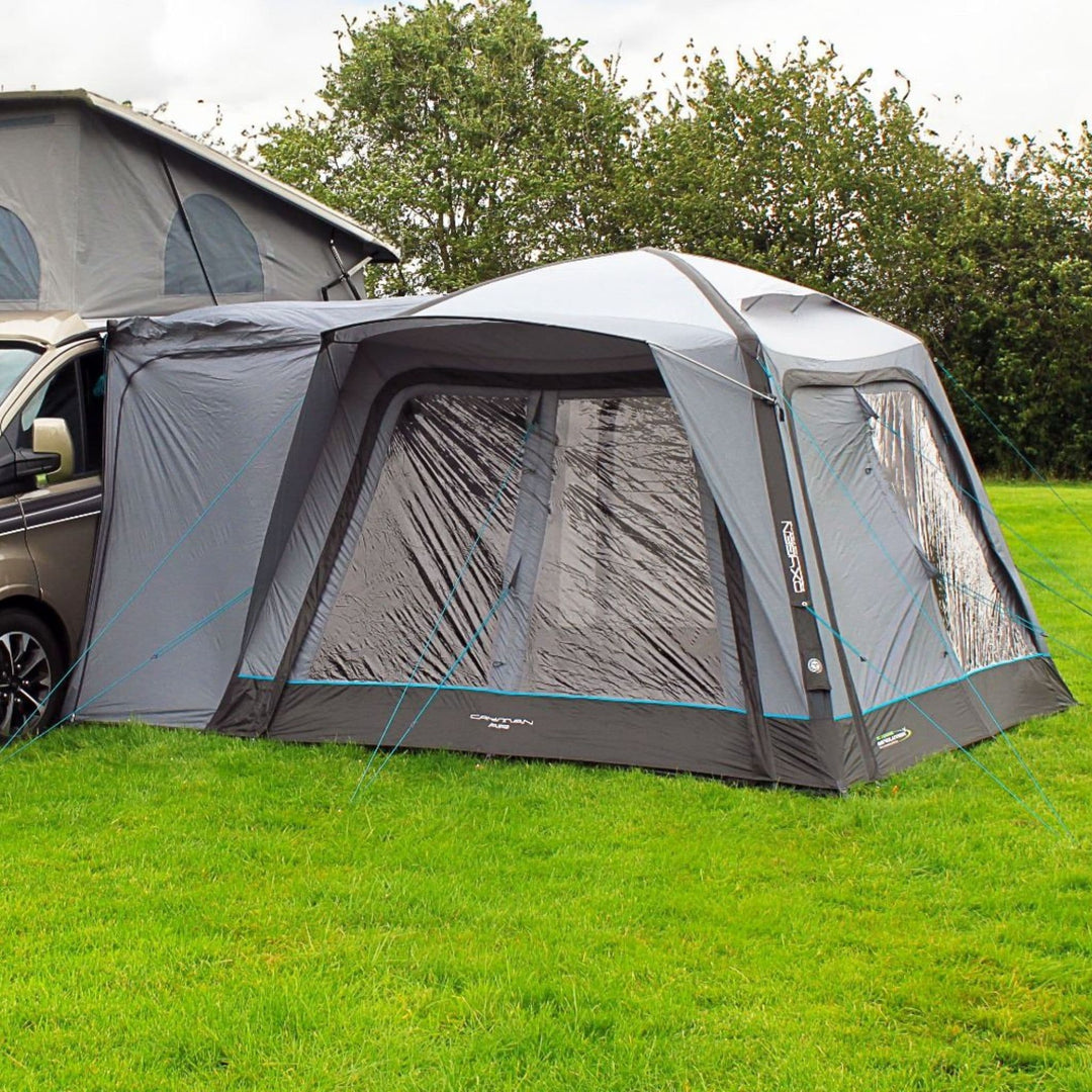 The Outdoor Revolution Cayman Air Low Drive Away Awning is shown attached to a VW campervan, featuring an inflatable structure designed for easy setup and spacious living.