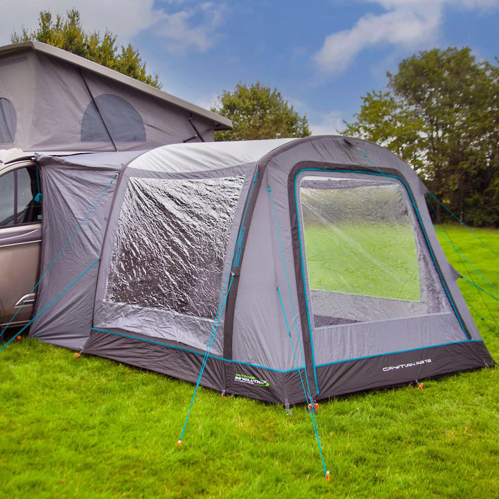 The Outdoor Revolution Cayman Air T2 Low drive away awning attached to a campervan, showcasing its sleek design and large clear windows for enhanced light inside. This inflatable drive away awning provides a secure and spacious fit, ideal for campervan adventures.