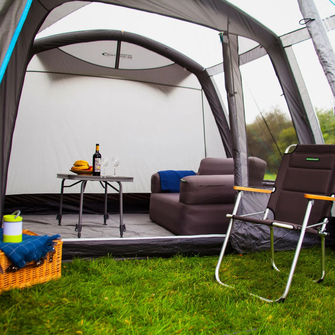 An interior view of the Outdoor Revolution Air Awning Cayman Air T3 Low, displaying the ample living space with chairs, a table, and a sofa arranged inside.