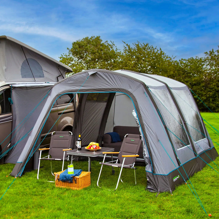 A side view of the Outdoor Revolution Cayman Air T3 Low awning connected to a campervan, showcasing the inflatable drive-away design with large clear windows and sturdy tensioned guy ropes.