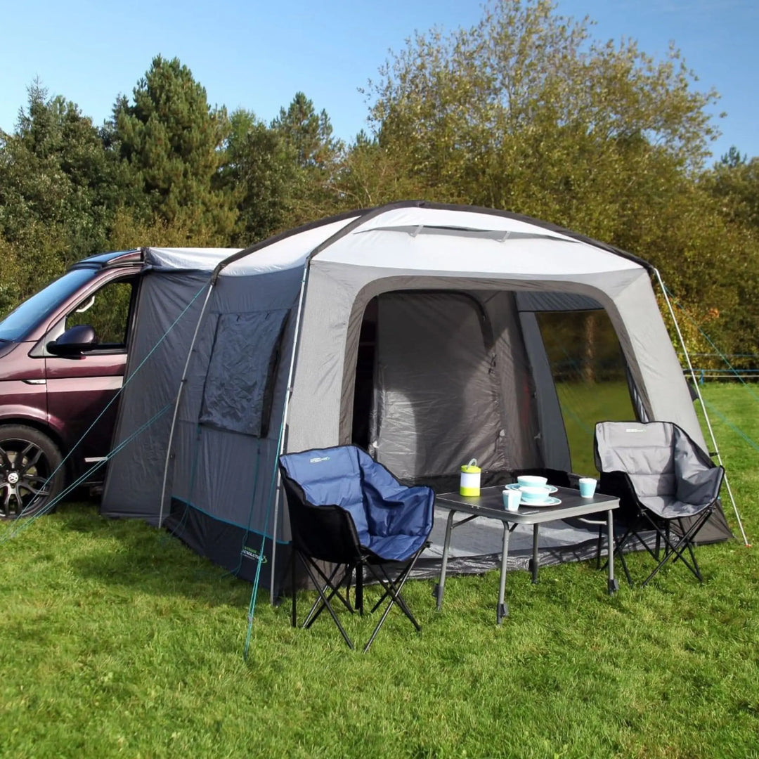 Camping setup with an Outdoor Revolution Cayman Cuda DT Awning, chairs, and a table outdoors.