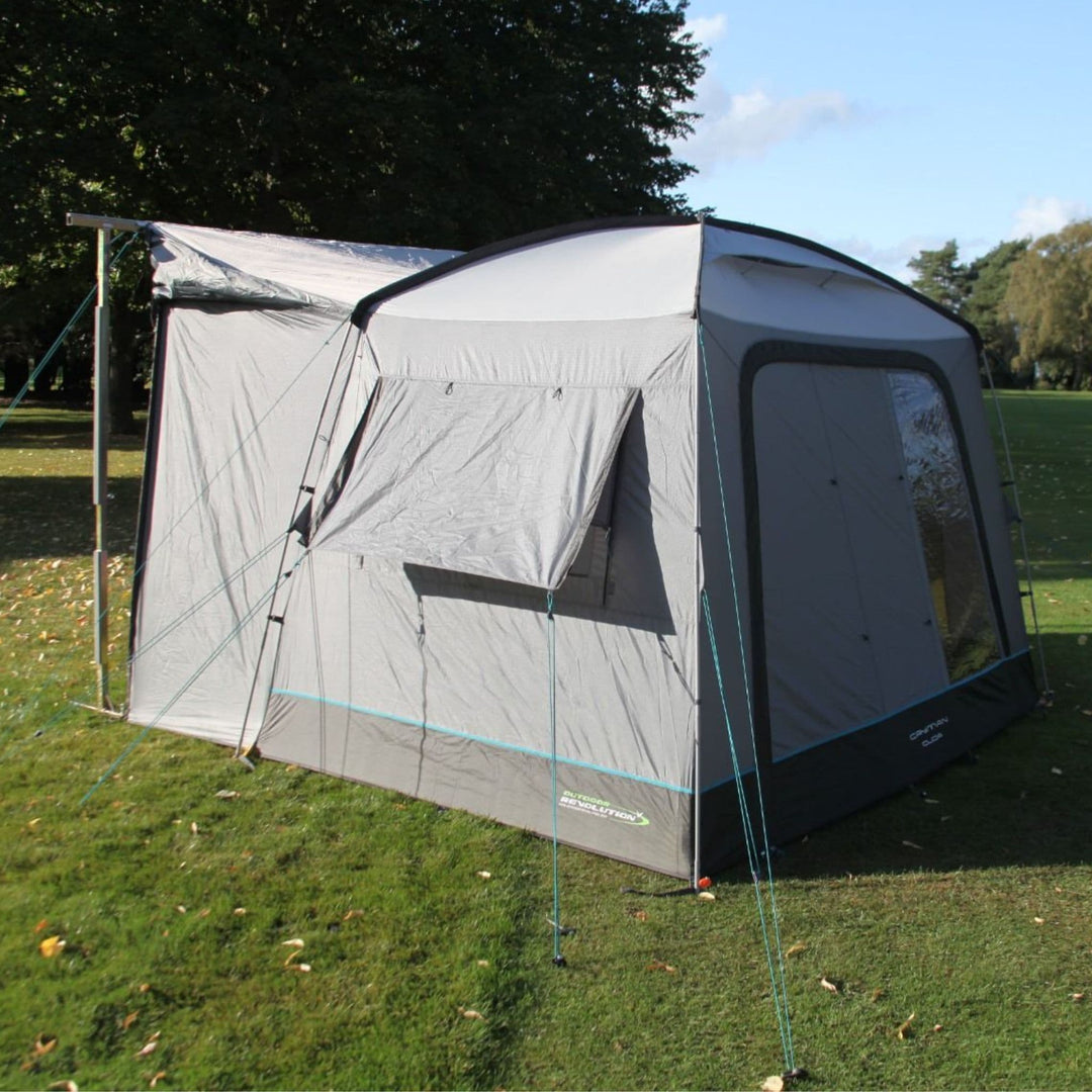 The Outdoor Revolution Cayman Cuda F/G Drive Away Awning is set up beside a campervan on a grassy field, showcasing its durable fibreglass frame and spacious design. This cayman cuda awning is ideal for camping trips requiring a reliable campervan drive away awning.