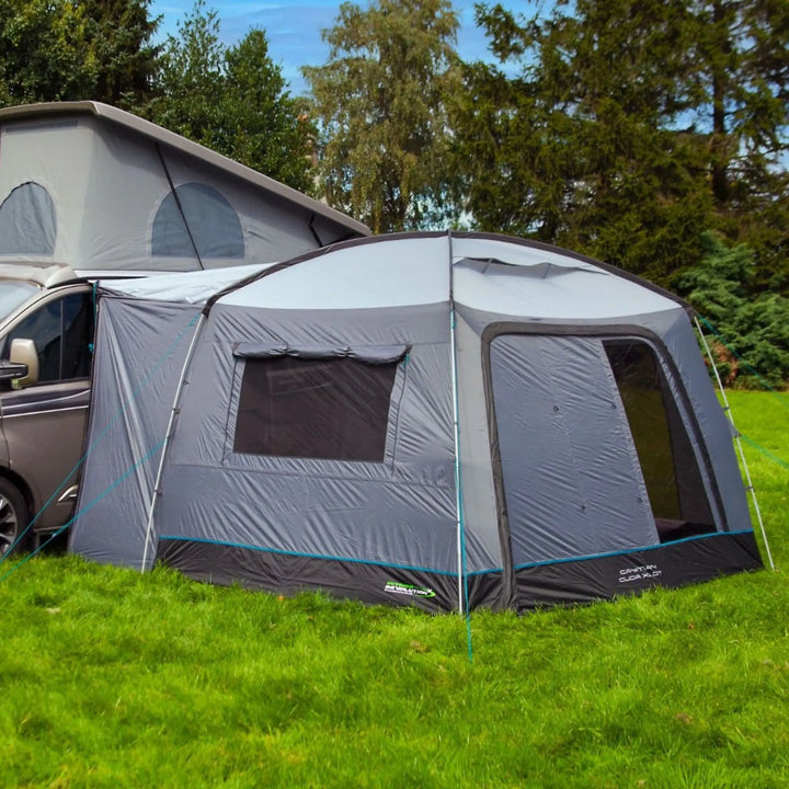 Campervan with an attached Outdoor Revolution Cayman Cuda XL DT drive-away awning on a grassy area with trees in the background