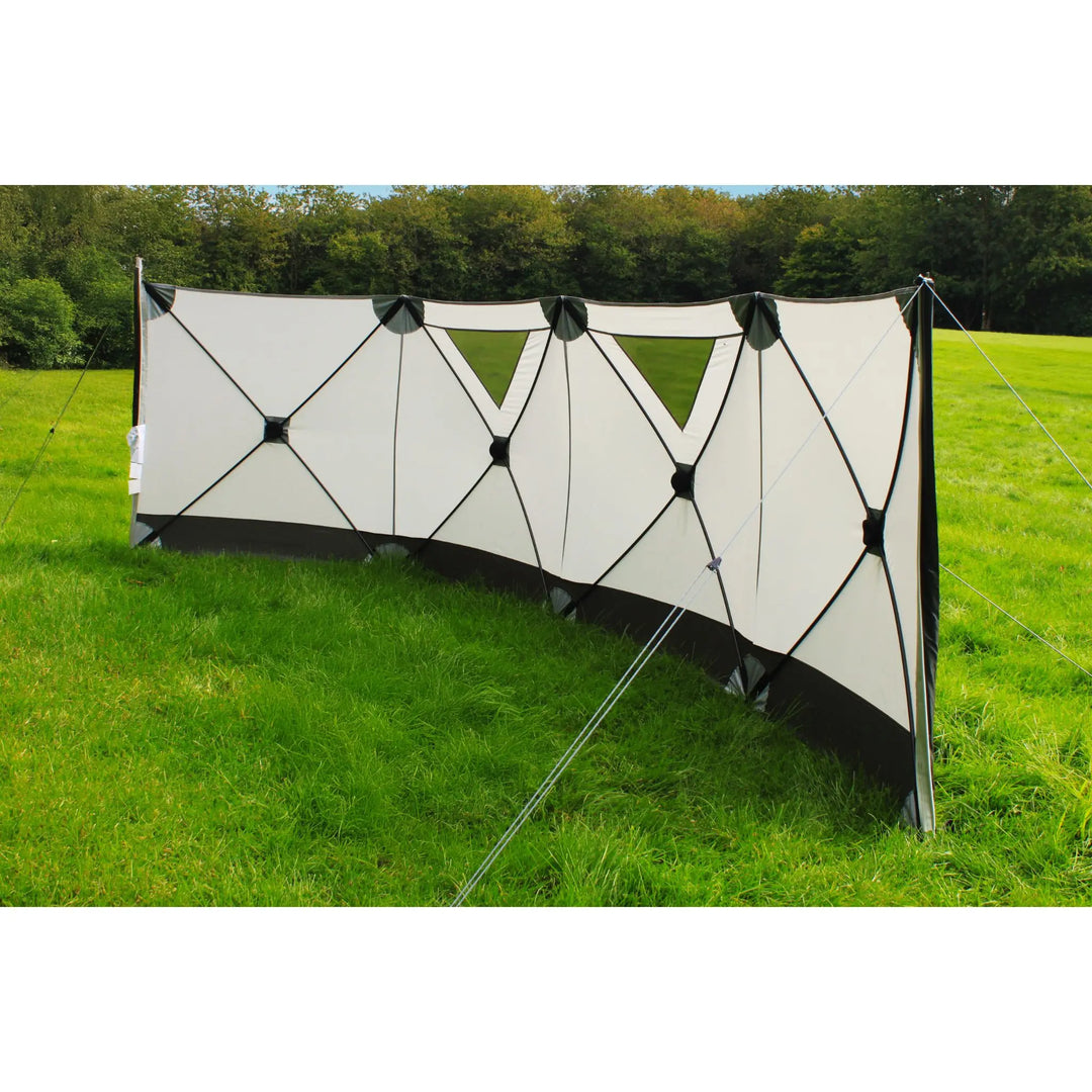 Outdoor Revolution Pronto 4 Windbreak set up on grassy field with guy lines secured, providing shelter and privacy for camping trips.