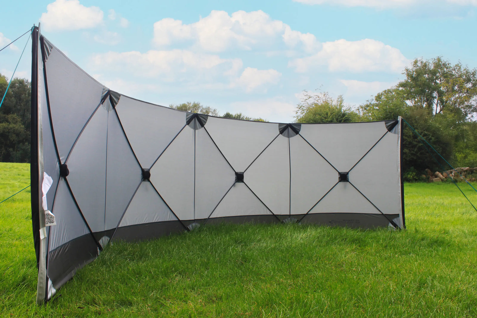 Outdoor Revolution Pronto Compact 4 windbreak providing shelter in an outdoor setting with lush greenery.