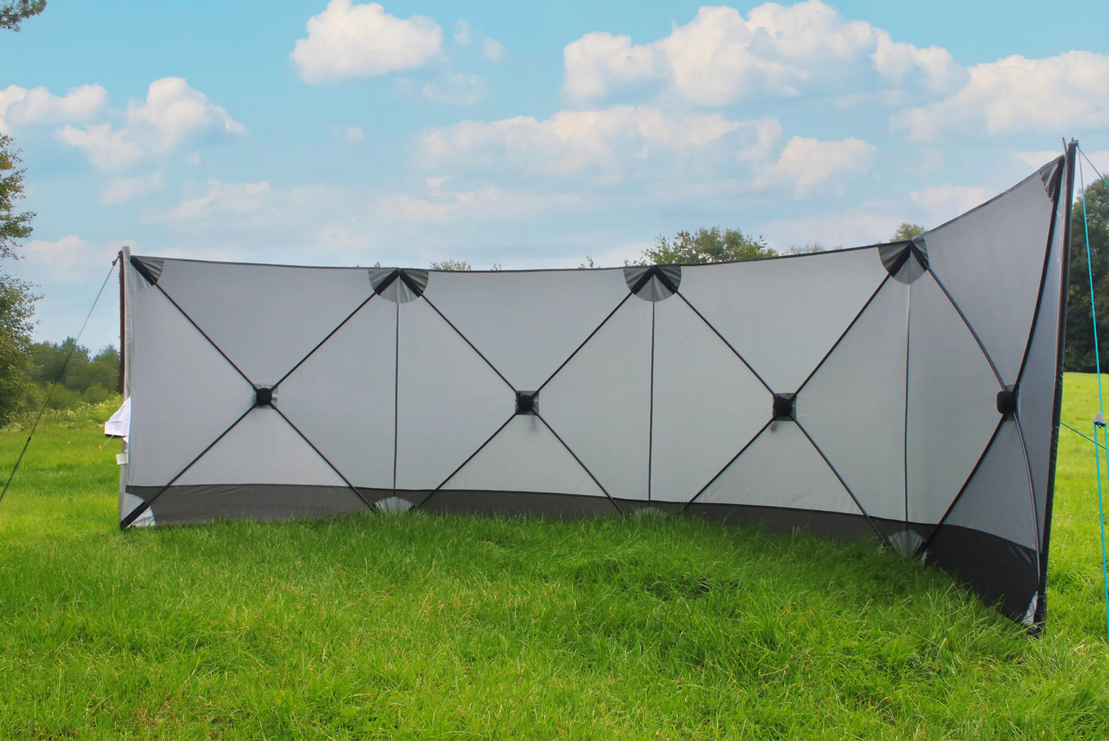 Outdoor Revolution Pronto Compact 4 windbreak set up in a curved formation in a scenic outdoor location.