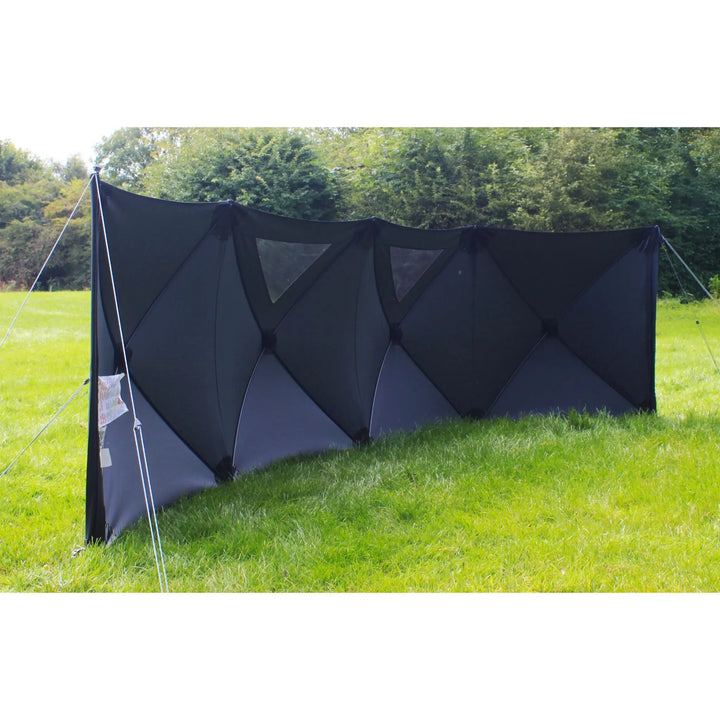 Angled view of the Outdoor Revolution Pronto Pro 4 Windbreak in a grassy outdoor setting with black panels and reflective windows.