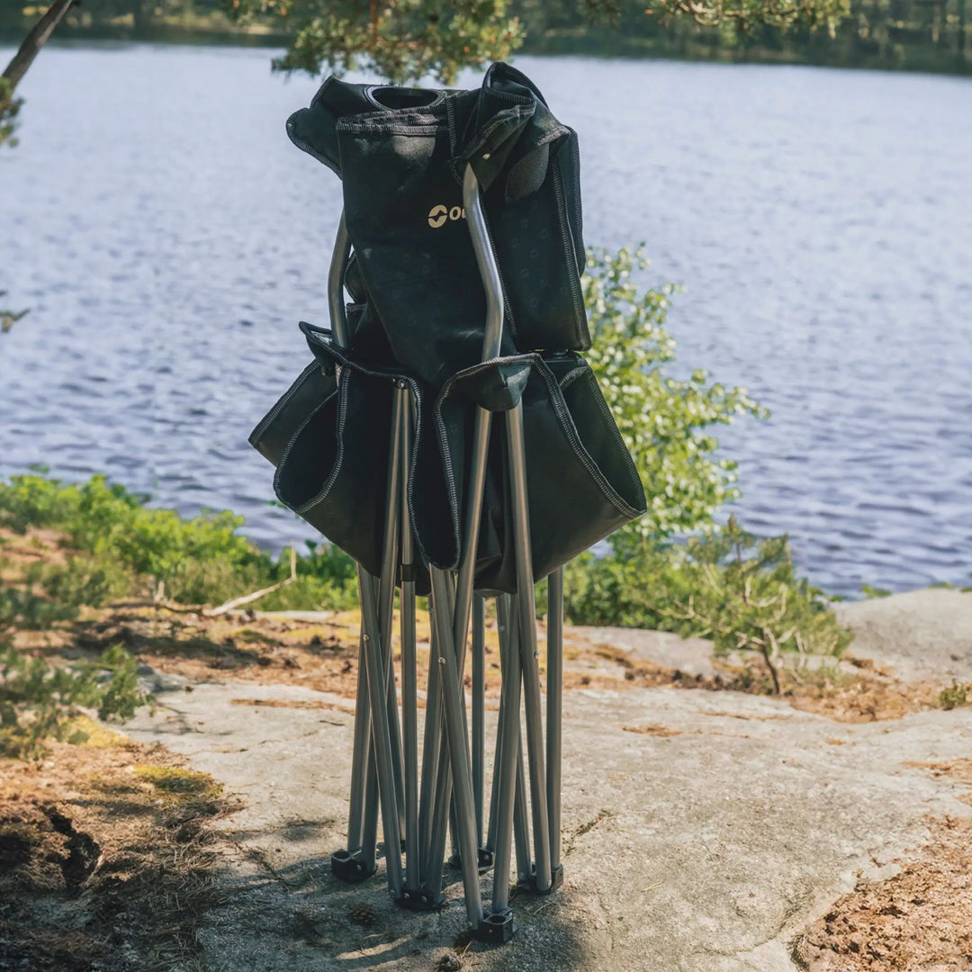 Outwell Catamarca Sofa folded with metal frame on a rock by a lake