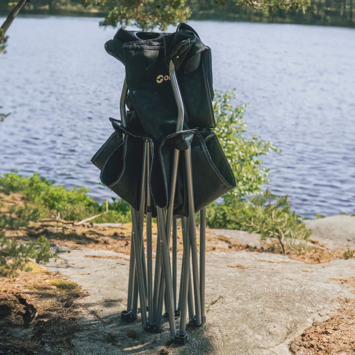 Outwell Catamarca Sofa folded with metal frame on a rock by a lake