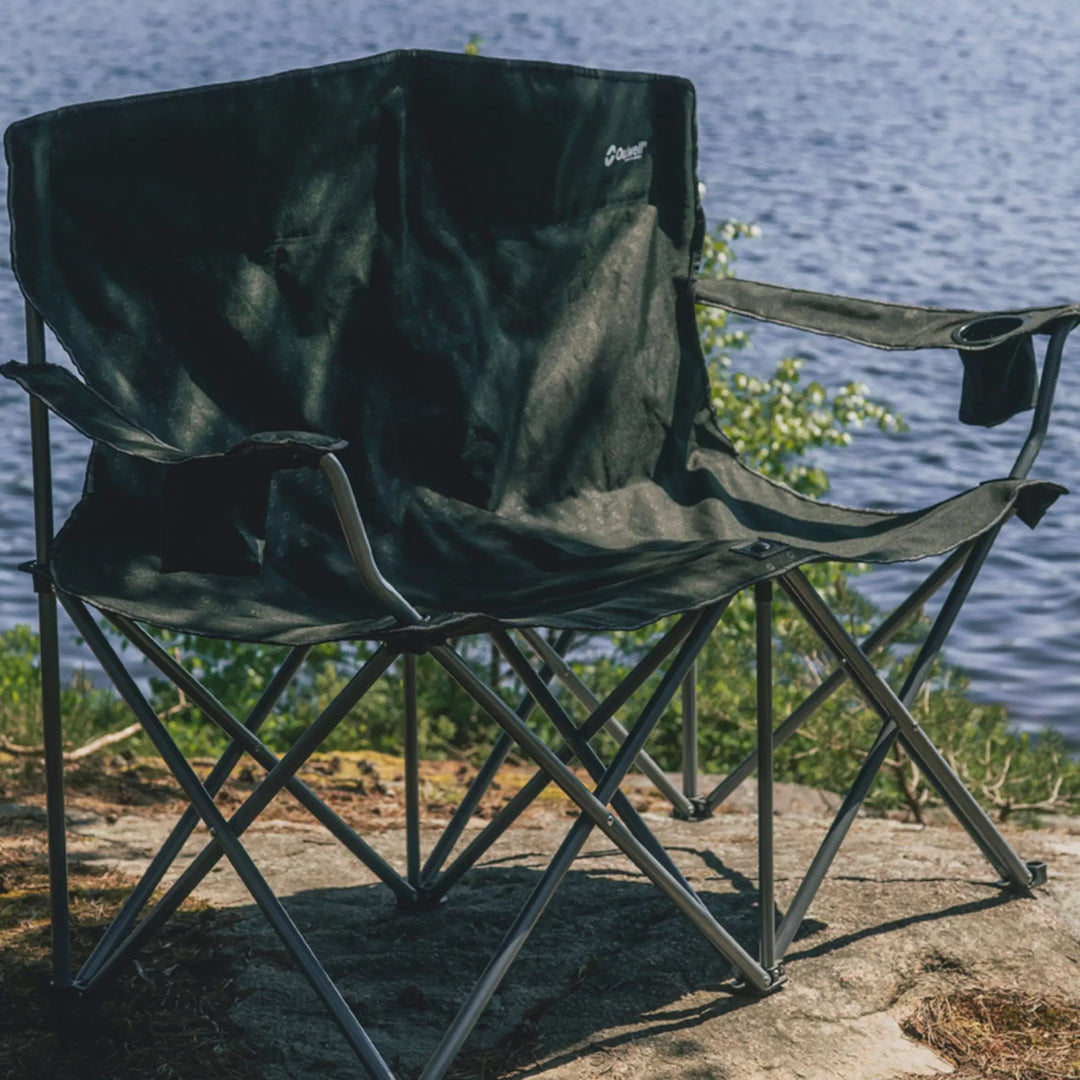 Outwell Catamarca Sofa with a brand logo on a rock by a lake.