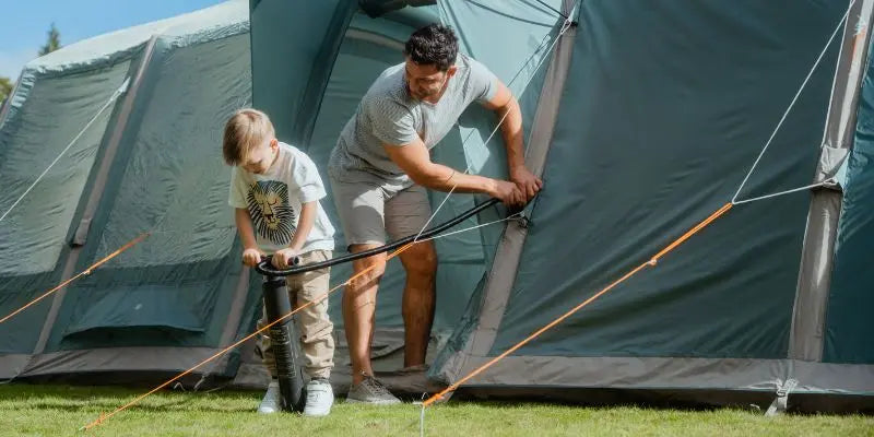 Man and child pumping up a Vango AirBeam tent together outdoors.