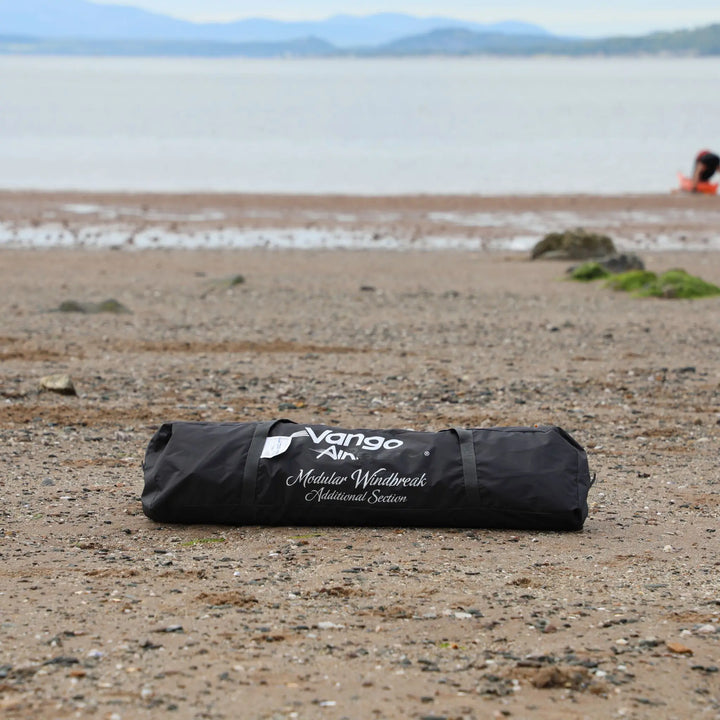 Vango AirBeam Modular Windbreak packed away in its carry bag on a beach with mountains in the background