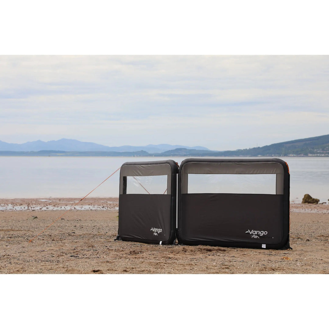 Vango AirBeam Modular Windbreak on a sandy beach with a body of water and mountains in the background.