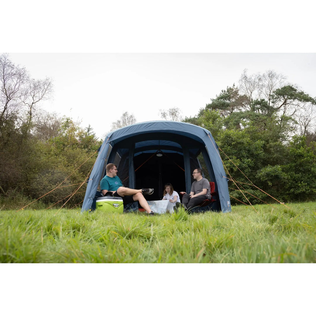 Group of campers relaxing inside the Vango Savannah Air 400 tent, set up on a grassy field. Highlighting its spacious porch area.