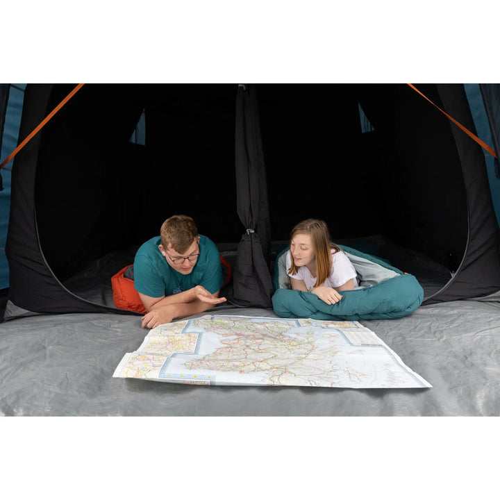 Two campers lying inside the Vango Savannah Air 400's darkened midnight bedrooms, looking at a map—designed for a restful night’s sleep in outdoor conditions.