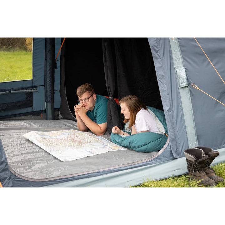 Campers inside the Vango Savannah Air 400 tent, lying on a sewn-in groundsheet and looking at a map—perfect for comfortable outdoor sleeping.