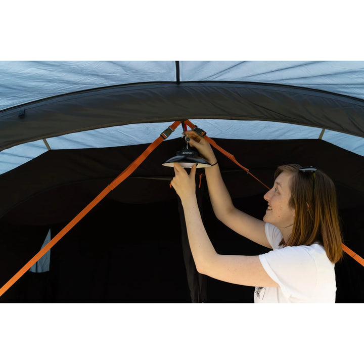 Camper attaching a lantern to the Vango Savannah Air 400 tent’s hanging point, ensuring well-lit nights for camping and glamping experiences.