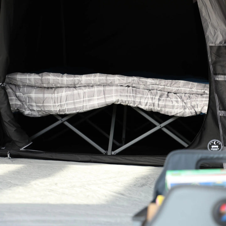 Foldable camp bed inside the Vango AirBeam Anantara IV Air 650XL premium tent, highlighting its spacious blackout bedroom area for a comfortable night's sleep.