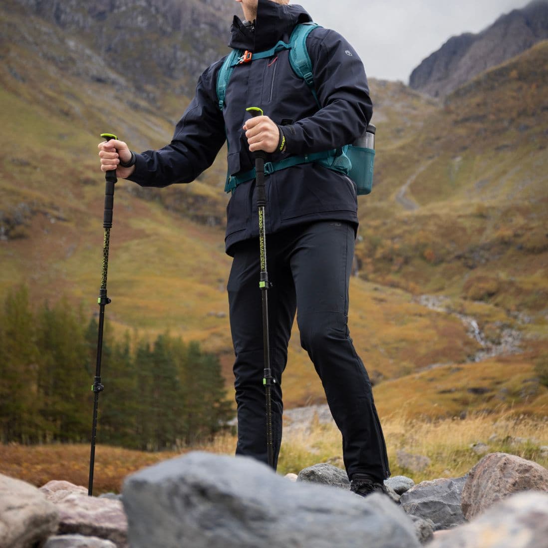 Lifestyle image of hiker using Vango Annapurna Walking Poles with green handle grips during trekking in the mountains.