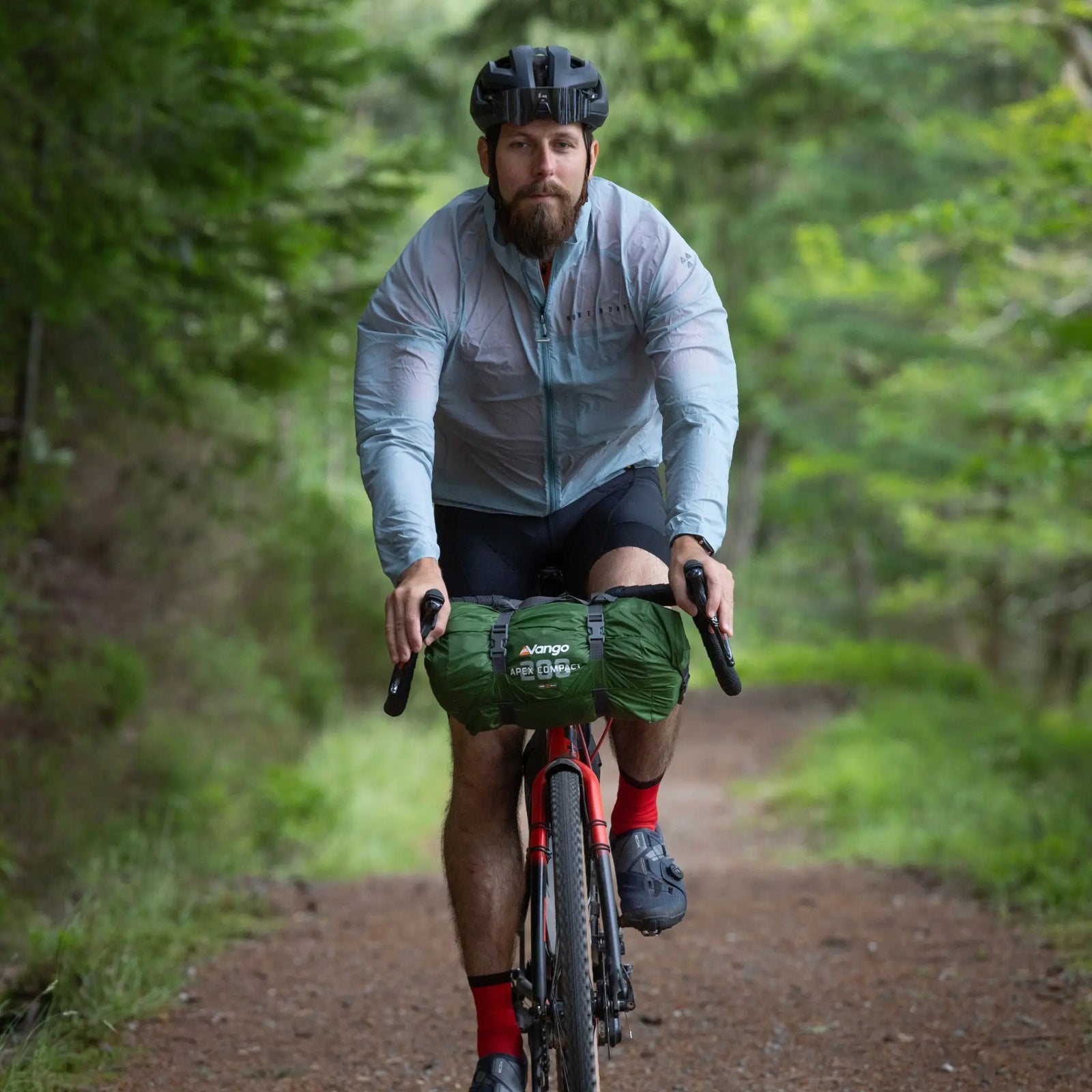 Cyclist on a forest trail with the Vango Apex Compact 200 Tent packed on the bike. A small pack size 2 man tent for trekking and adventures.