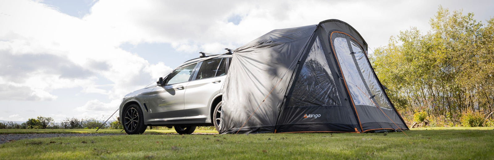 Vango Arden Tailgate Awning set up in a scenic outdoor location, connected to an SUV and showcasing its practical design.