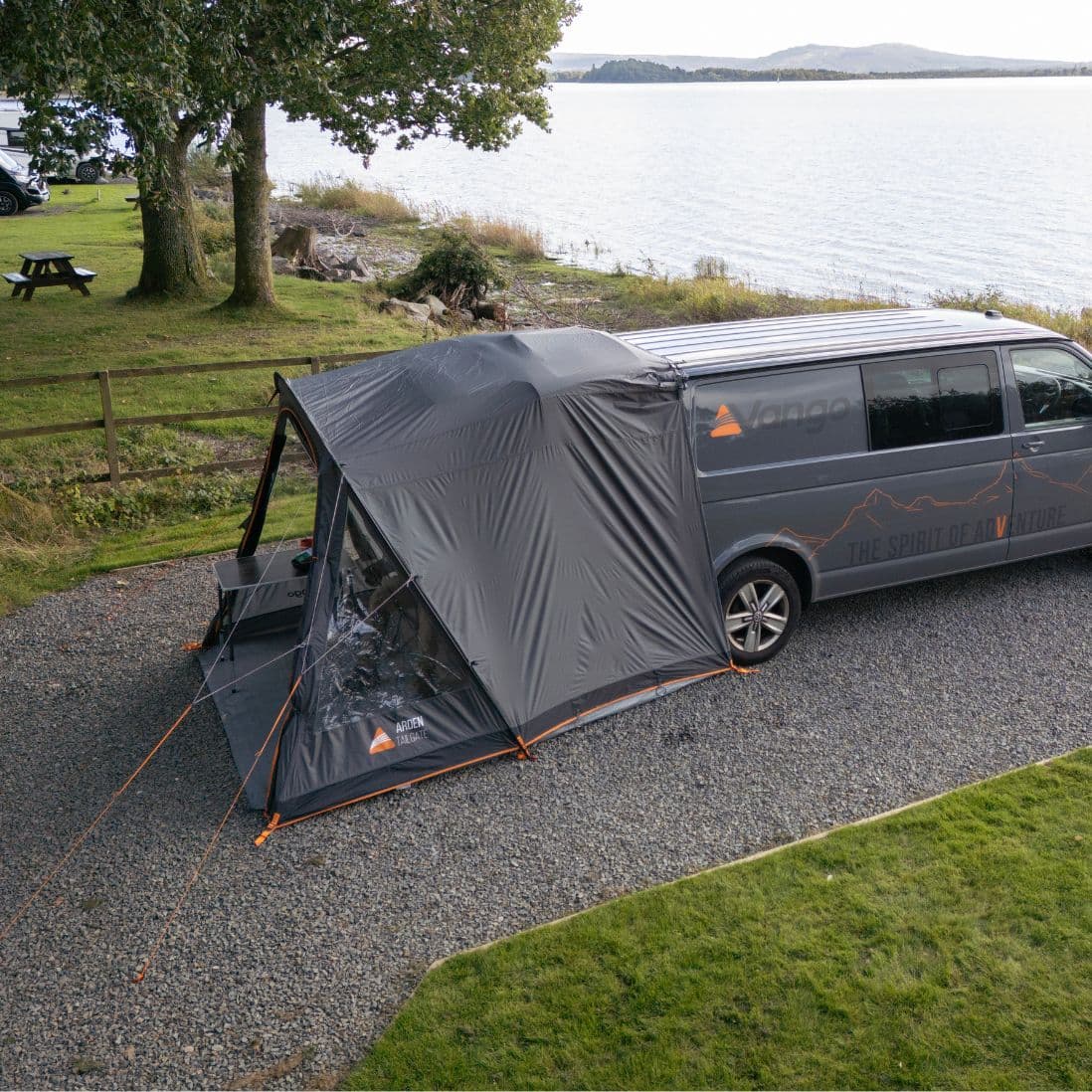 Aerial view of the Vango Arden Tailgate Awning attached to a campervan in a picturesque camping setting.